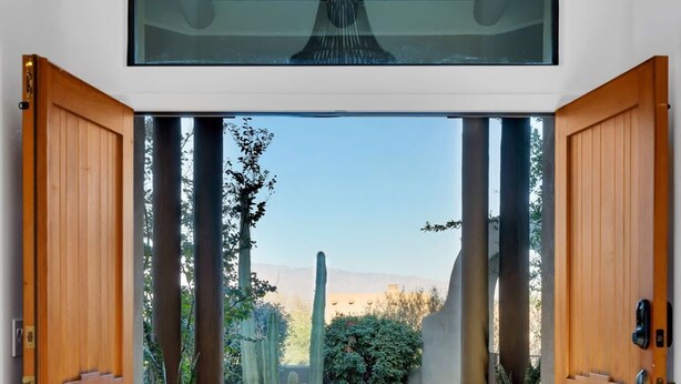 An open wooden door leading to a patio with a view of cacti and a clear sky. - Casa Milagro - A designer desert retreat! (Tucson)