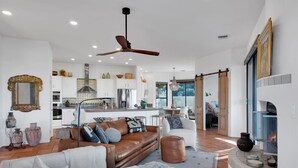 A spacious living area with a brown leather sofa, a white armchair, and a fireplace. - Casa Milagro - A designer desert retreat! (Tucson)