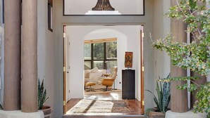 A modern entrance with a wooden archway, a rug, and a view into a living area with a sofa and a coffee table. - Casa Milagro - A designer desert retreat! (Tucson)