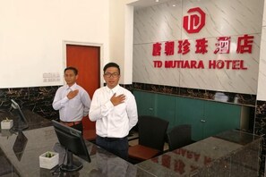 A reception area with a reception desk, a computer monitor, and a wall with a hotel sign. - TD Mutiara Hotel (Semporna)