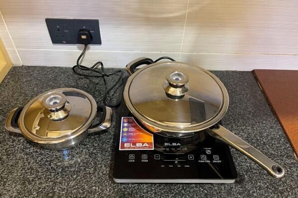 A kitchen with an electric stove and two pots on it.
