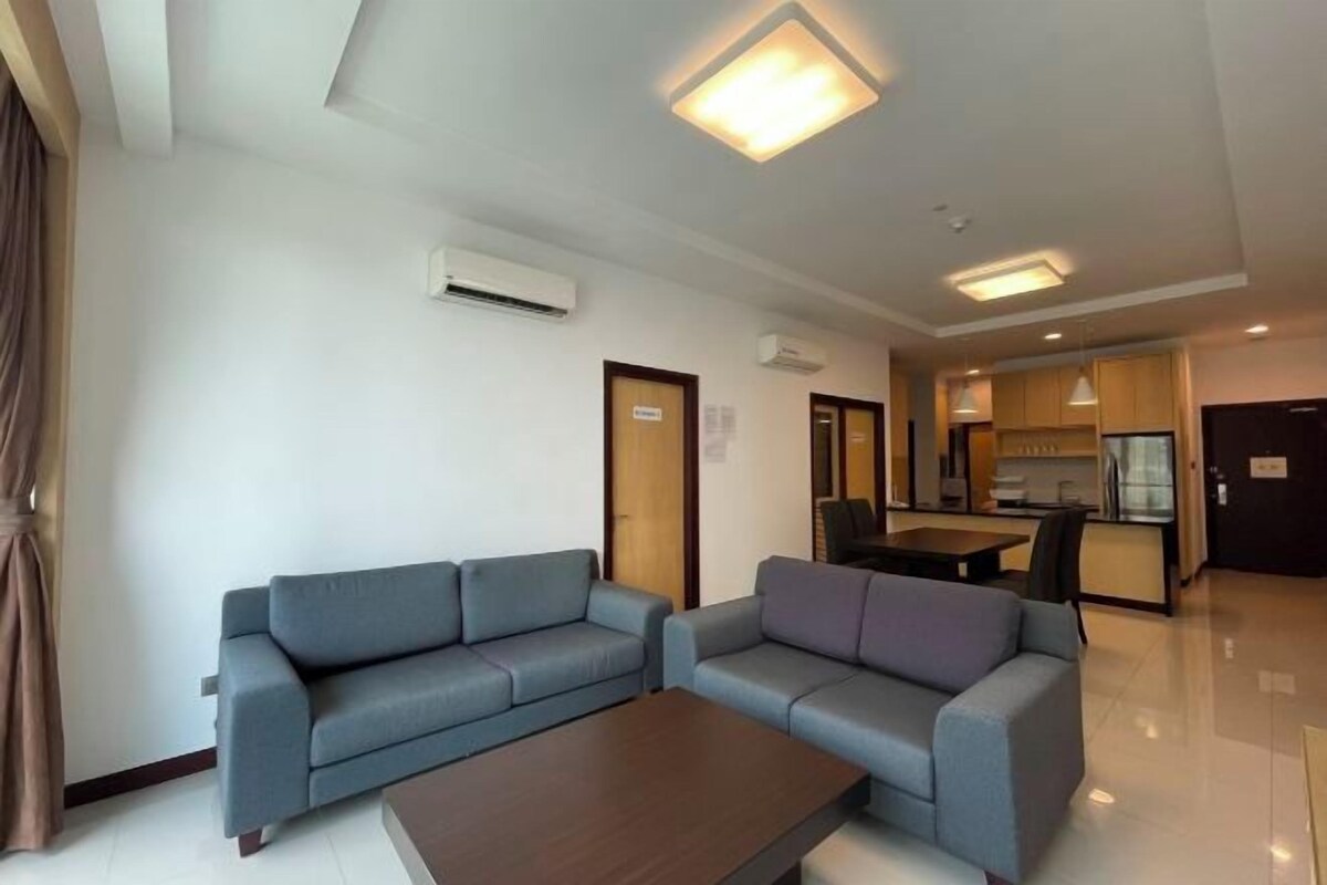 A modern living room with two sofas, a coffee table, and a kitchen area in the background.