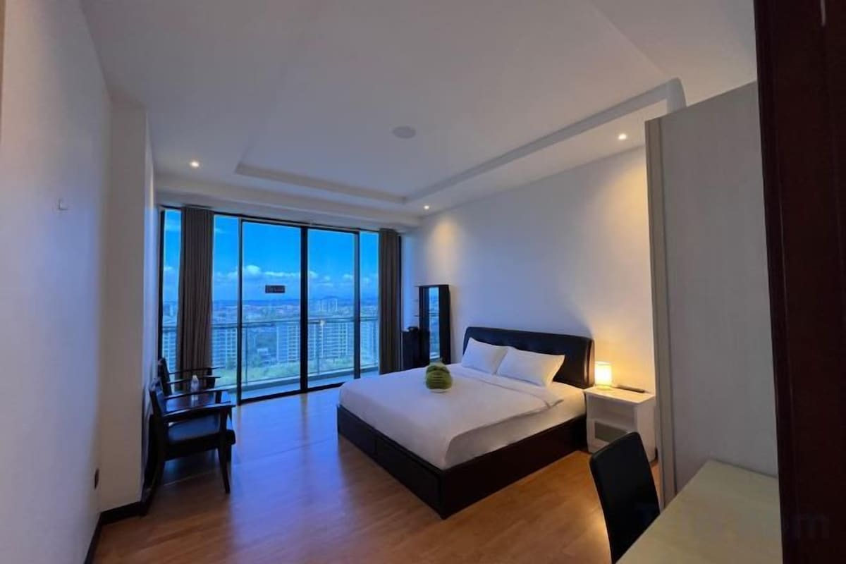 A modern hotel room with a large bed, a desk, and a view of the city.