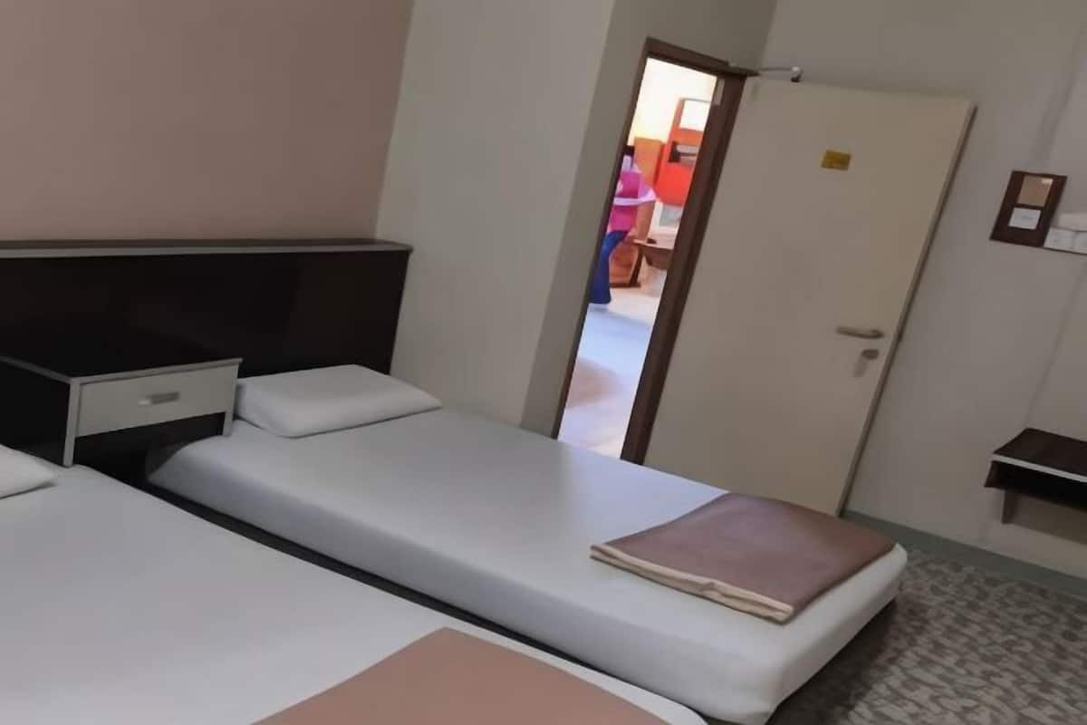 Ein Hotelzimmer mit zwei Einzelbetten, einem Schreibtisch, einem Stuhl und einem Kleiderschrank.