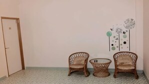 A room with two wicker chairs, a small round table, and a door. - Marina Hotel Kemaman (Chukai)