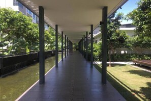 A covered walkway with a water feature on one side and a grassy area on the other. - Paradise Suite at the Loft, Imago (Kota Kinabalu)