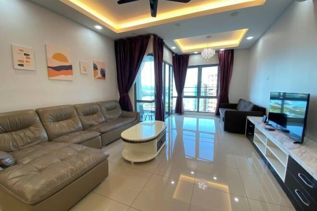 A modern living room with a leather sofa, a coffee table, a TV, and artwork on the walls.