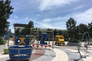 A playground with various play structures, including a blue swing set and climbing frames. - Paradise Suite at the Loft, Imago (Kota Kinabalu)