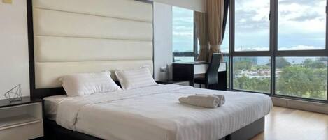 A modern hotel room with a large bed, a desk, and a view of the city.