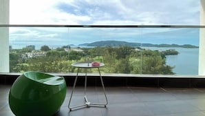 A room with a large window, a green chair, and a small table with a red object. - Paradise Suite at the Loft, Imago (Kota Kinabalu)