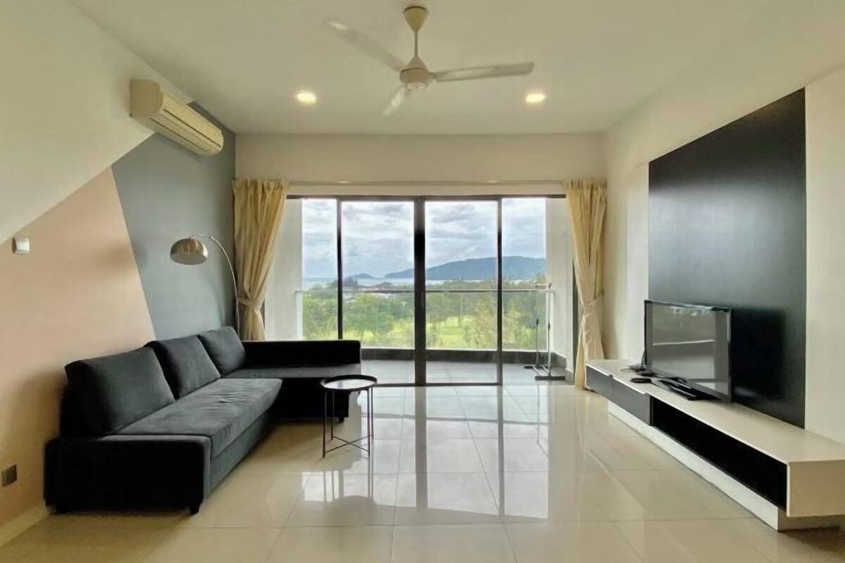 A modern living room with a sofa, TV, and large windows.
