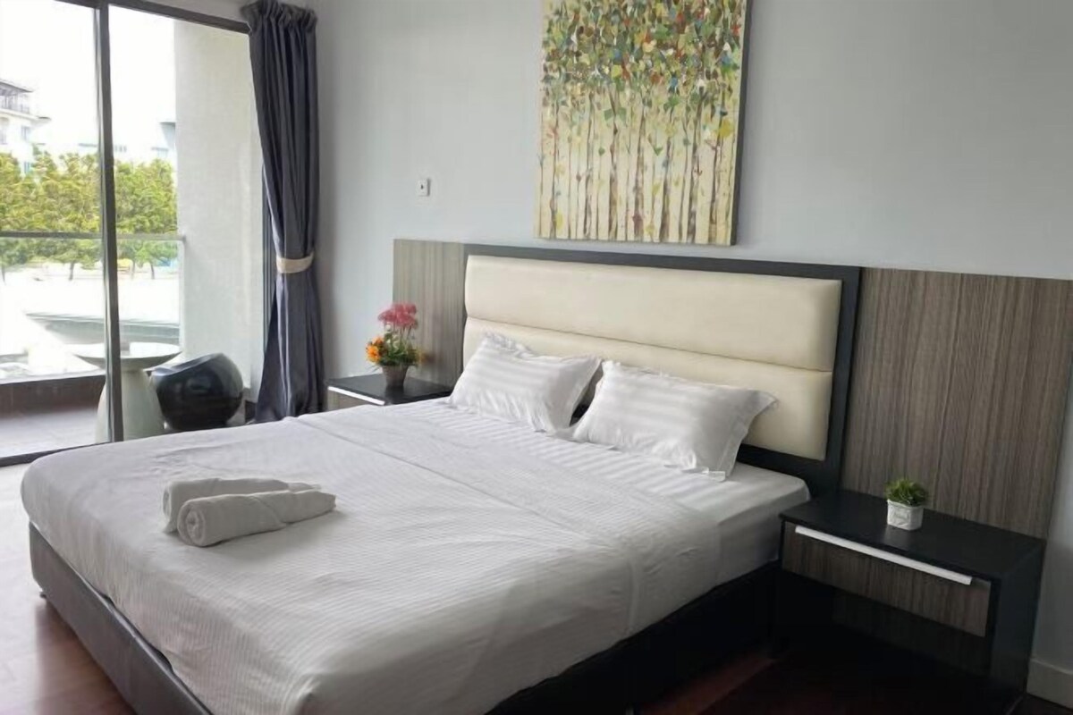 Habitación de hotel con una cama grande, una mesita de noche, una pequeña mesa, una planta en maceta y un ventanal con vistas.