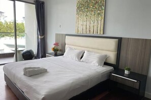Habitación de hotel con una cama grande, una mesita de noche, una pequeña mesa, una planta en maceta y un ventanal con vistas.