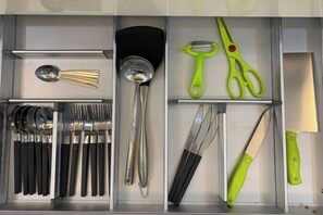 A kitchen drawer with utensils and tools, including a spoon, spatula, and green-handled scissors. - Paradise Suite at the Loft, Imago (Kota Kinabalu)