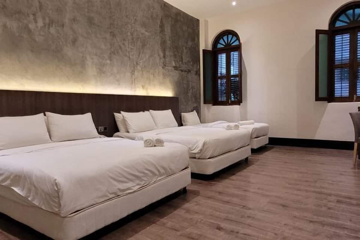 A hotel room with three beds, a large window with a view, and a wooden floor.
