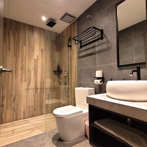 Ein modernes Badezimmer mit einer Duschkabine aus Holz, einer Toilette, einem Waschbecken mit Spiegel und einem Handtuchhalter.