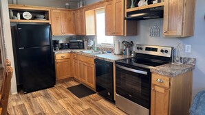 A kitchen with wooden cabinets, a black refrigerator, a microwave, a stove, and a dishwasher.