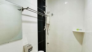 A bathroom with a toilet, a hand dryer, a mirror, and a shower area. - Charisma Hotel (Kuala Kuantan)