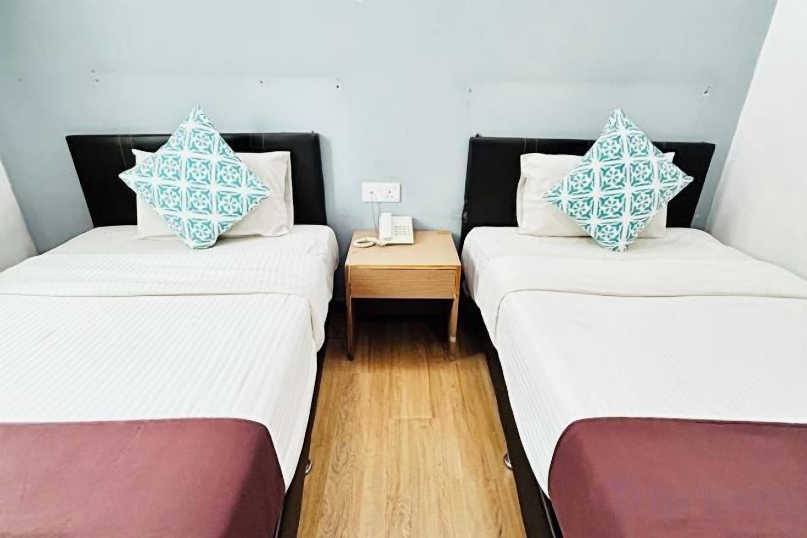 A hotel room with two beds, a nightstand, and a wooden floor.