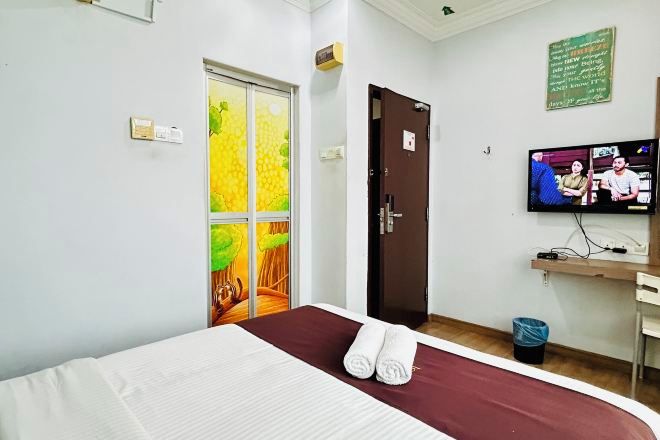 Ein Hotelzimmer mit einem Bett, einem Fernseher, einer Tür und einer Wand mit einem grünen Schild.