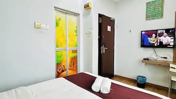 Een hotelkamer met een bed, een televisie, een deur en een muur met een groen bord.