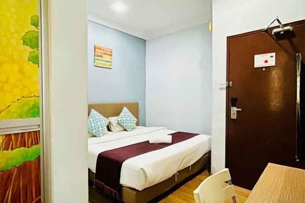 Een hotelkamer met een bed, een houten stoel en een deur met een bordje.
