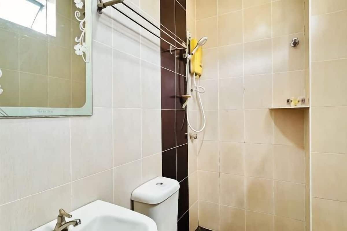 A bathroom with a sink, mirror, shower, and toilet.