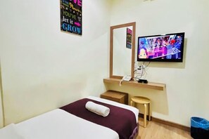 A hotel room with a bed, a television mounted on the wall, a small stool, and a trash bin. - Charisma Hotel (Kuala Kuantan)