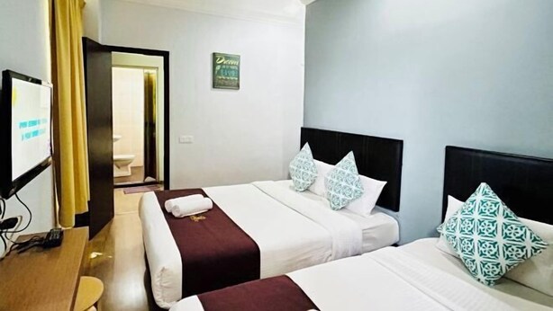A hotel room with two beds, a TV, a desk, and a bathroom visible through an open door. - Charisma Hotel (Kuala Kuantan)