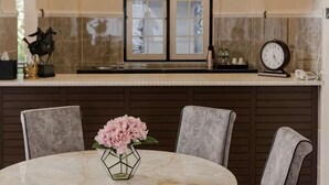 A round marble table with two chairs, a vase with pink flowers, and a clock on the wall. - SpringHill Resort (Brinchang)