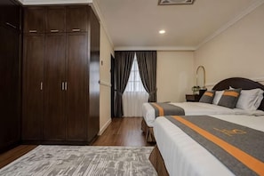 Habitación de hotel con armario, cama con colcha a rayas, mesita de noche y ventana con cortinas.
