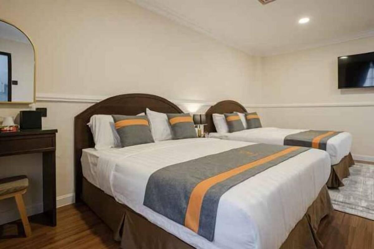 A hotel room with two beds, a desk, a chair, a TV, and a mirror.