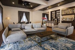 A modern living room with a sectional sofa, a smaller sofa, a coffee table, and a bookshelf. - SpringHill Resort (Brinchang)