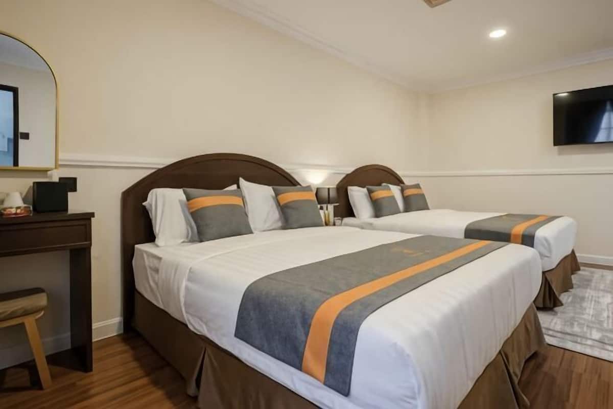 A hotel room with two beds, a desk, a chair, a TV, and a mirror.