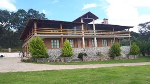 Un bâtiment à deux étages, avec une base en pierre et une structure supérieure en bois, doté d’un balcon et de nombreuses fenêtres.