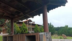 Un bâtiment à la structure en bois, doté de piliers en pierre et d’un chemin en pierre.