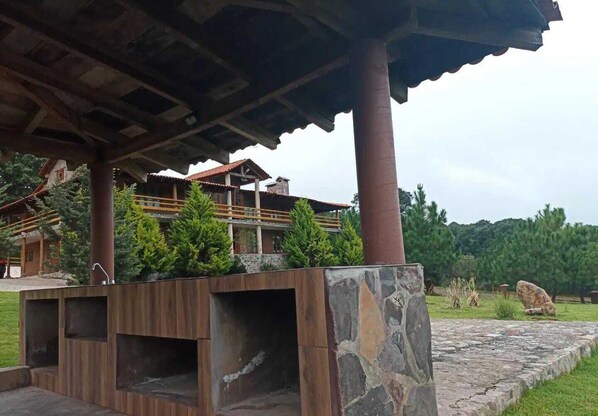 Un bâtiment à la structure en bois, doté de piliers en pierre et d’un chemin en pierre.