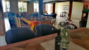 Un espace repas avec une longue table dressée pour le repas, entourée de chaises.