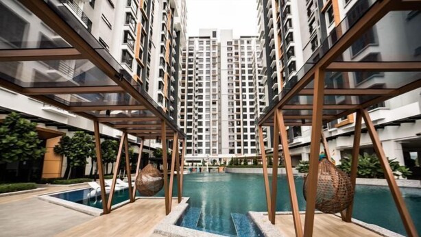 A modern residential building with a central swimming pool, surrounded by balconies and wooden structures.