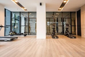 A modern gym with exercise equipment, large windows, and a wooden floor. - K Avenue by CAIRO (Donggongon)