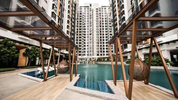 A residential building with a swimming pool, wooden deck, and modern architecture.