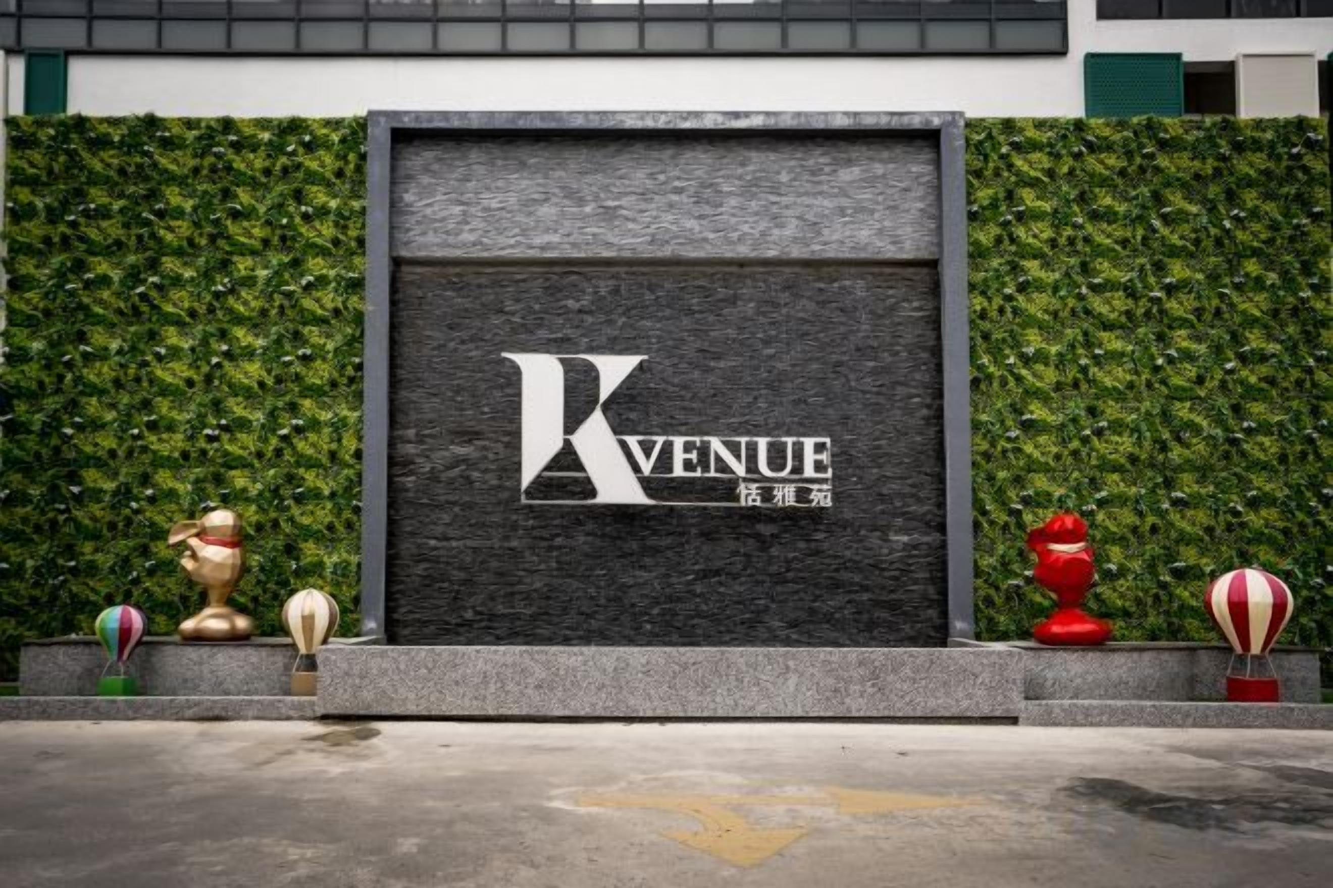A building facade with a sign that reads 'KVENUE' and a green hedge.