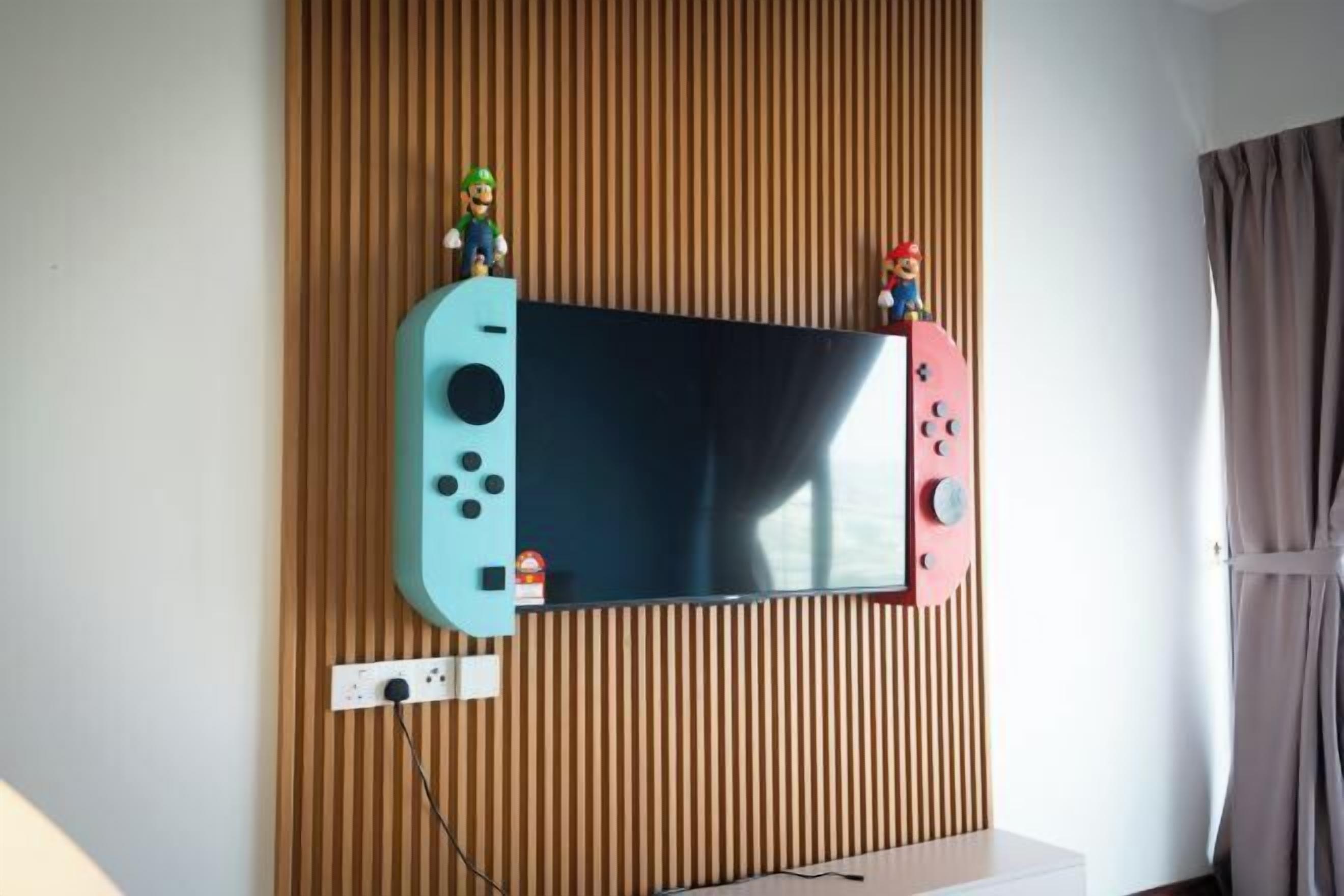 Ein an der Wand befestigter Fernseher mit je einer Mario-Figur an jeder Seite.