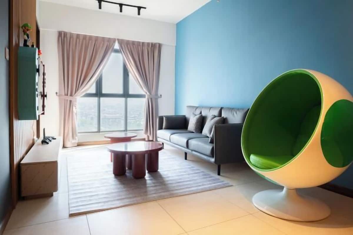 Un salon moderne avec un canapé, un fauteuil vert et blanc, une table basse et une vue dégagée grâce à de grandes fenêtres.