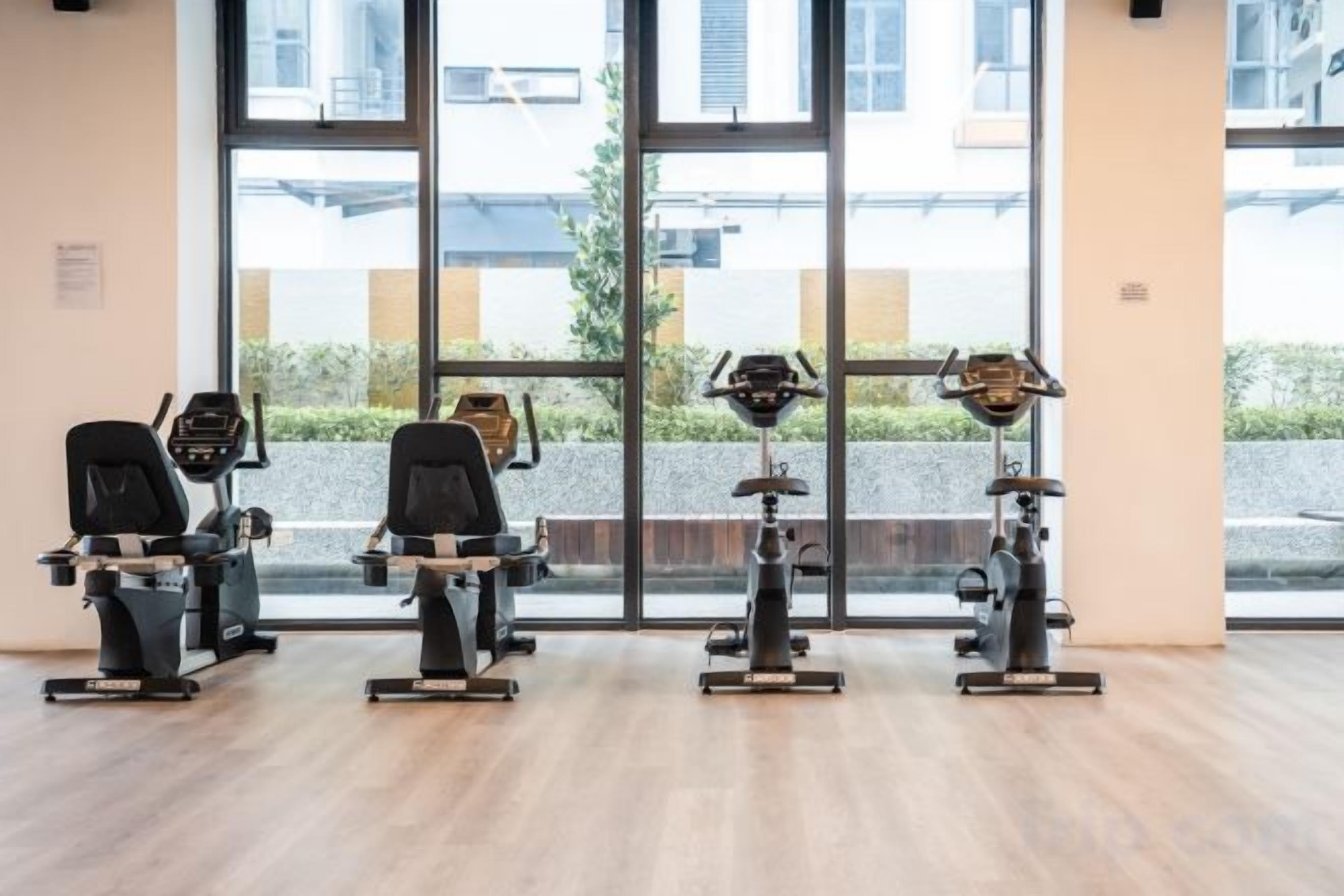 A gym with cardio machines and a large window.