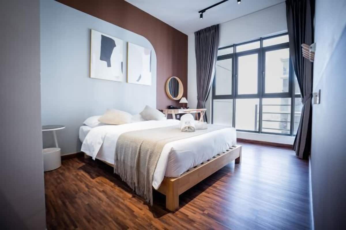 Une chambre d’hôtel moderne avec un grand lit, un miroir rond et une vue sur la ville.