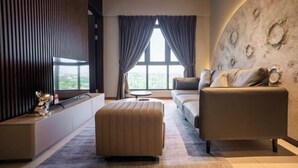 A modern living room with a sofa, ottoman, and a large window with curtains.
