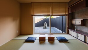 Ein traditioneller japanischer Raum mit Tatami-Bodenbelag, Shoji-Schirm und Blick auf einen Garten.