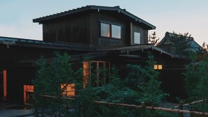 Ein zweistöckiges Holzhaus mit einem großen Fenster im Obergeschoss und einem kleineren Fenster im Untergeschoss.