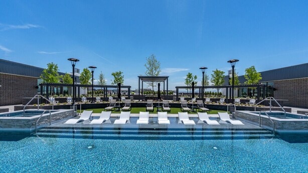 Uma área de piscina moderna com espreguiçadeiras e um gazebo.